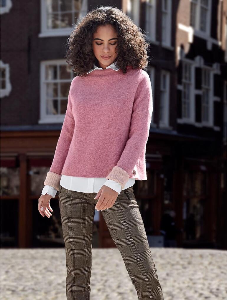 Vrouw met roze walkpullover op een geplaveide straat