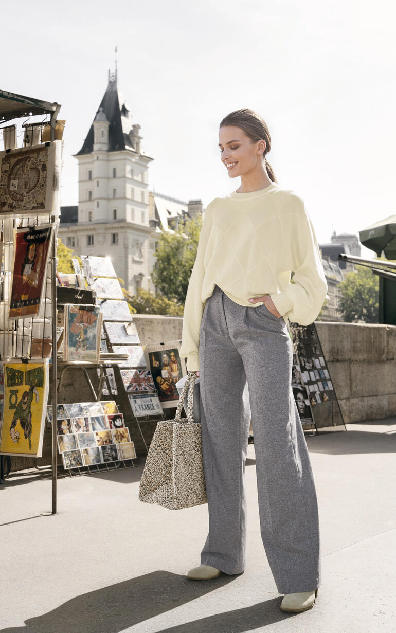 Dames trui in lichtgeel, los en casual met grijze broek.