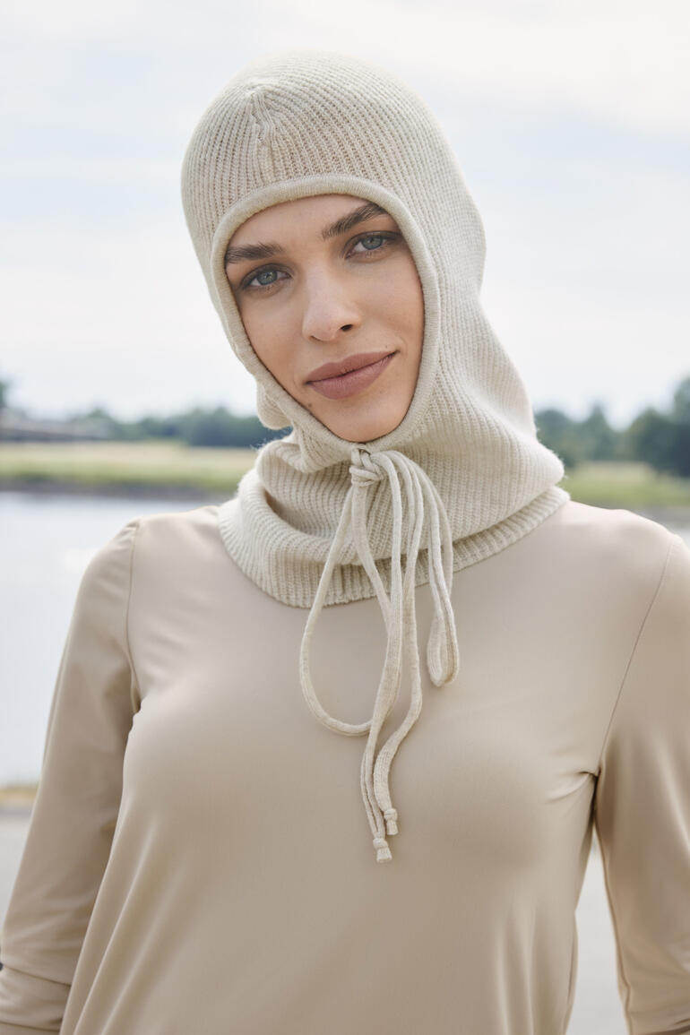 Vrouw draagt ecru gebreide balaclava met trekkoord