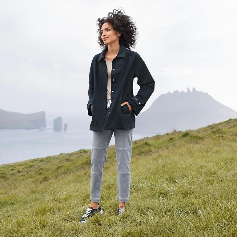 Vrouw in zwarte Ilse Jacobsen regenjack staat op het gras.