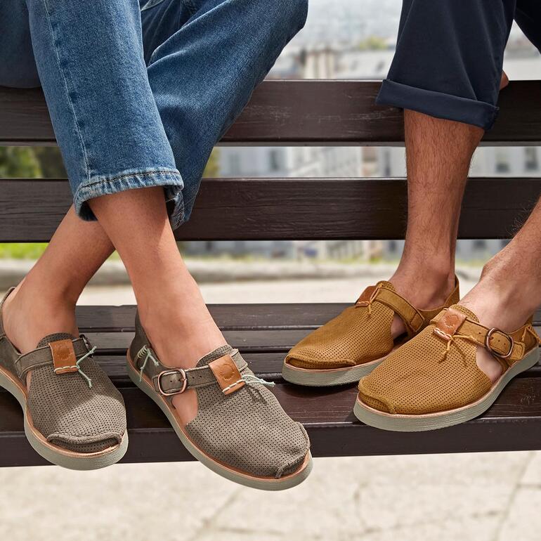 taupe en cognac Twee personen dragen Satorisan sneaker-sandalen op een bank