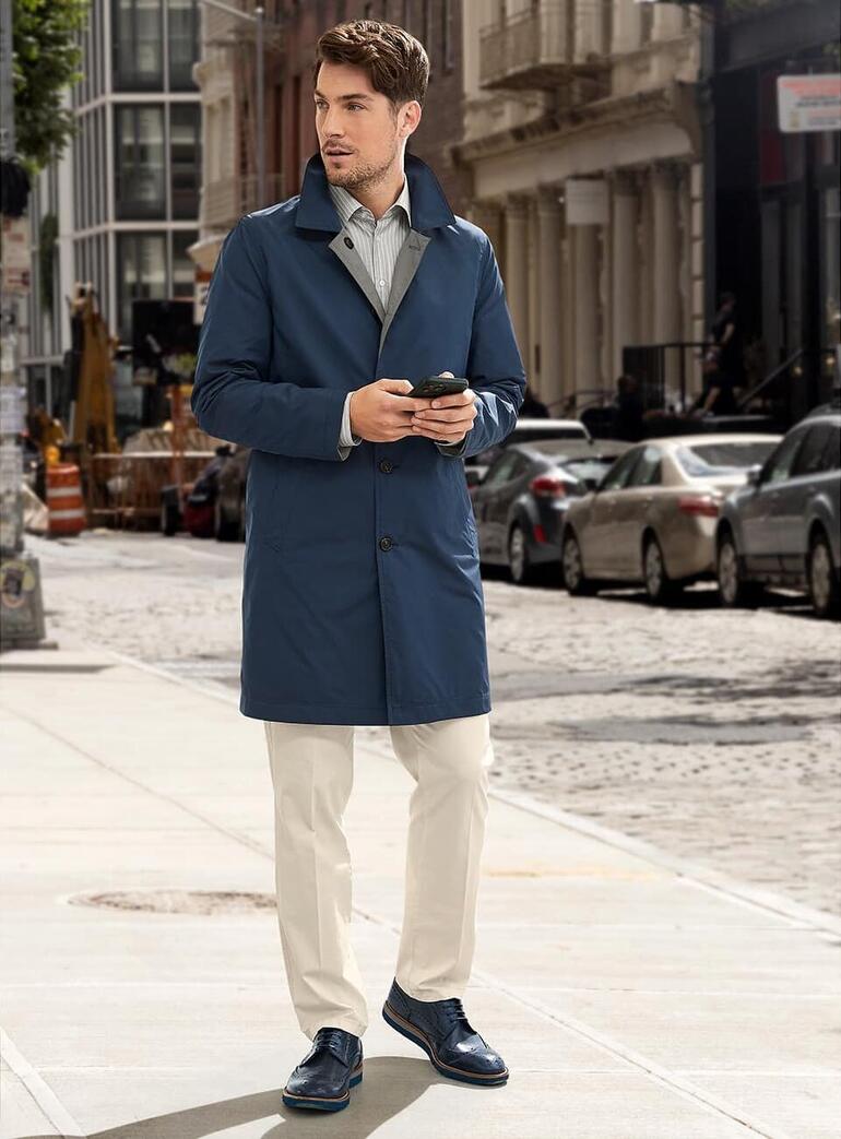 Man in een blauwe omkeerjack op straat met een smartphone