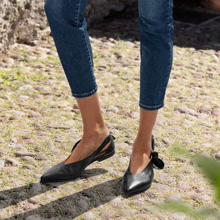 Zwarte 2-in-1 ballerina's van voren, gedragen door een vrouw in jeans.