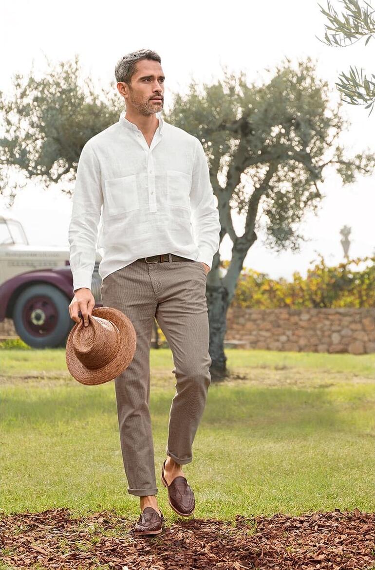 Pied-de-poule zomer-chino Man in een licht linnen overhemd met een strohoed in een mediterrane omgeving.