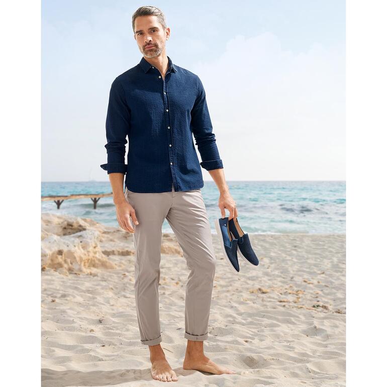 lichtbeige Man in donkerblauw seersucker jeanshemd voor een traditioneel gebouw.
