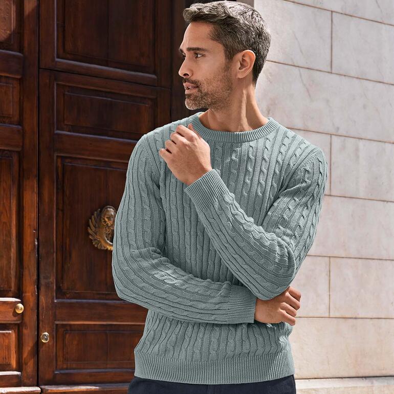 Close-up van een man in Carbery linnen kabeltrui in een stedelijke omgeving.