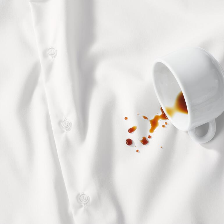 Wit overhemd met koffievlek en kopje ernaast.