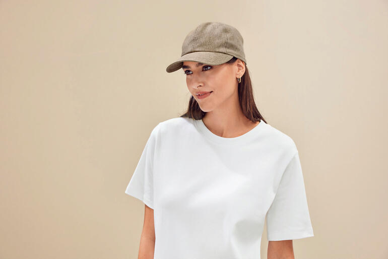 zandkleur Vrouw in een licht T-shirt met een basecap en een glimlach.