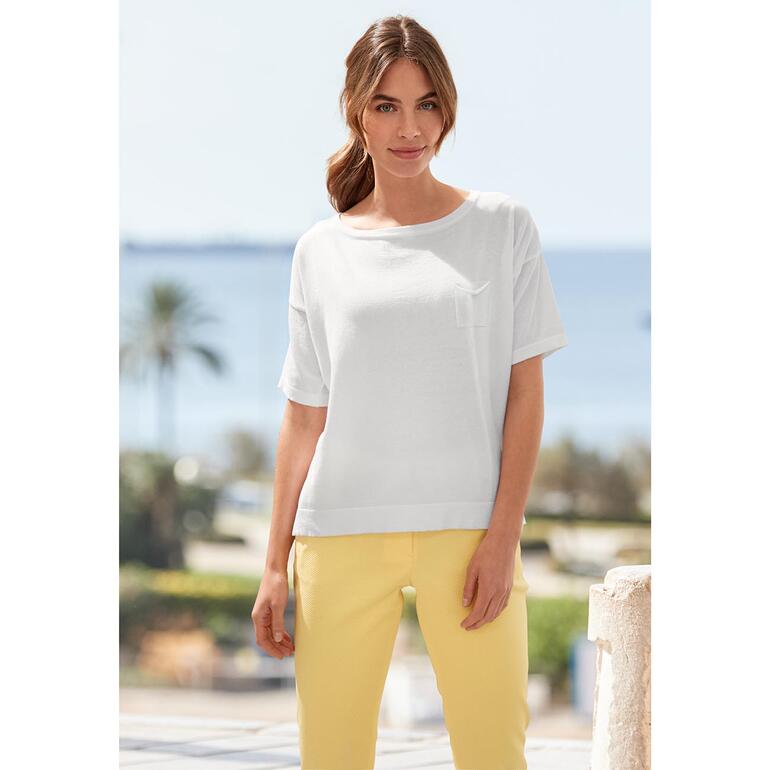 Vrouw in een wit t-shirt met korte mouwen en gele broek.