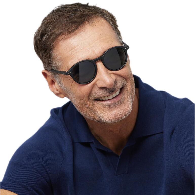 zonnebril, zwart Man met een zonnebril glimlacht, draagt een donkerblauwe poloshirt.