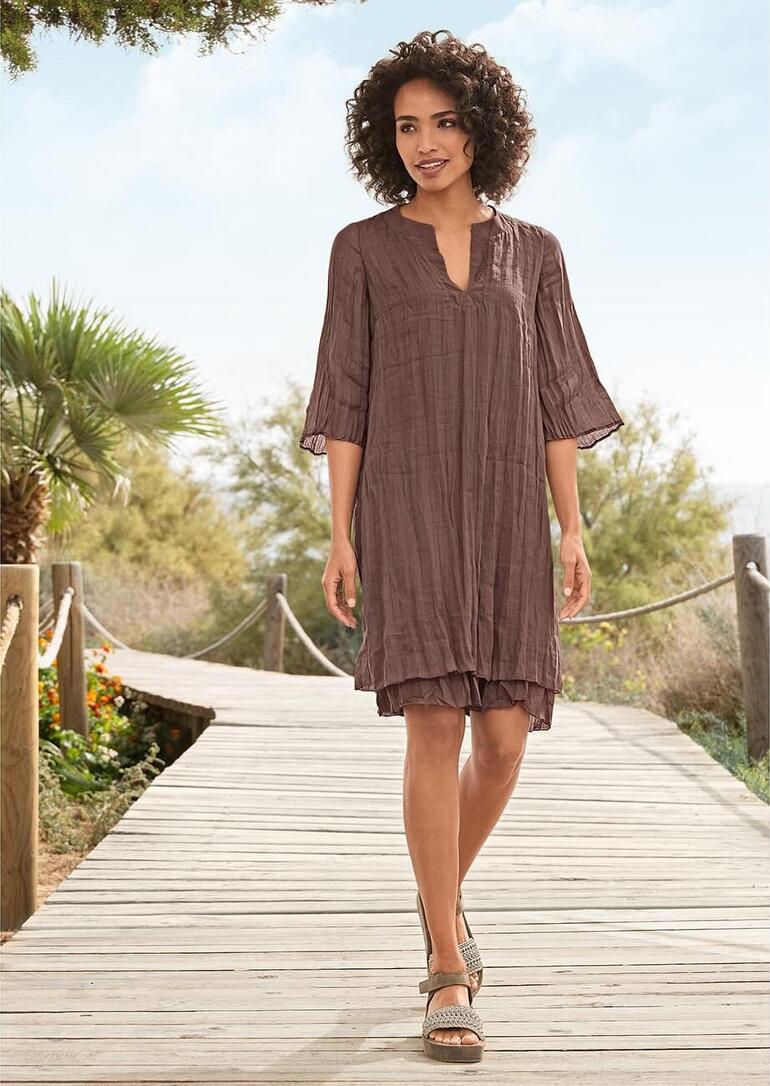 Vrouw in chocolade layering-kleed op een houten pad.