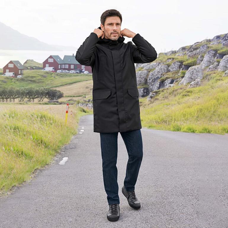 Eurex by Brax wollen jeans Man in een zwarte jas en wollen jeans op een pad.