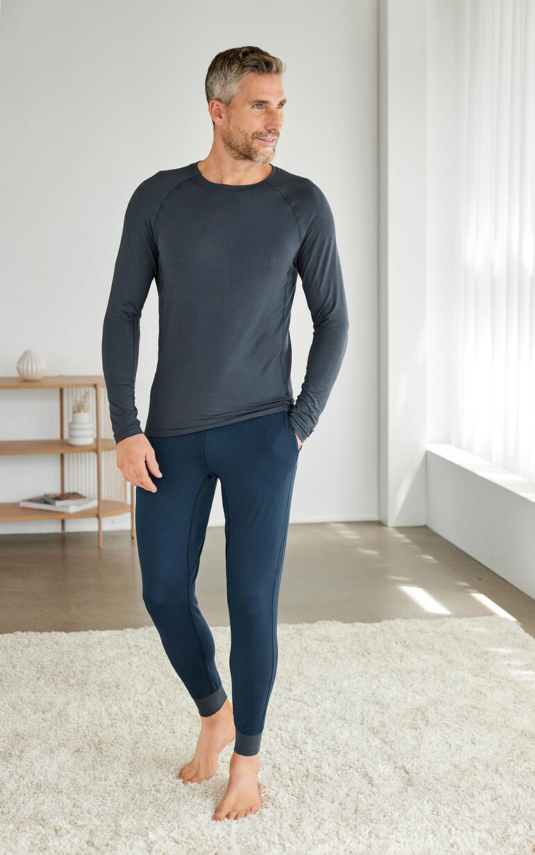 Man in Dagsmejan pyjama, bestaande uit een langhemd en leggings in donkergrijs.