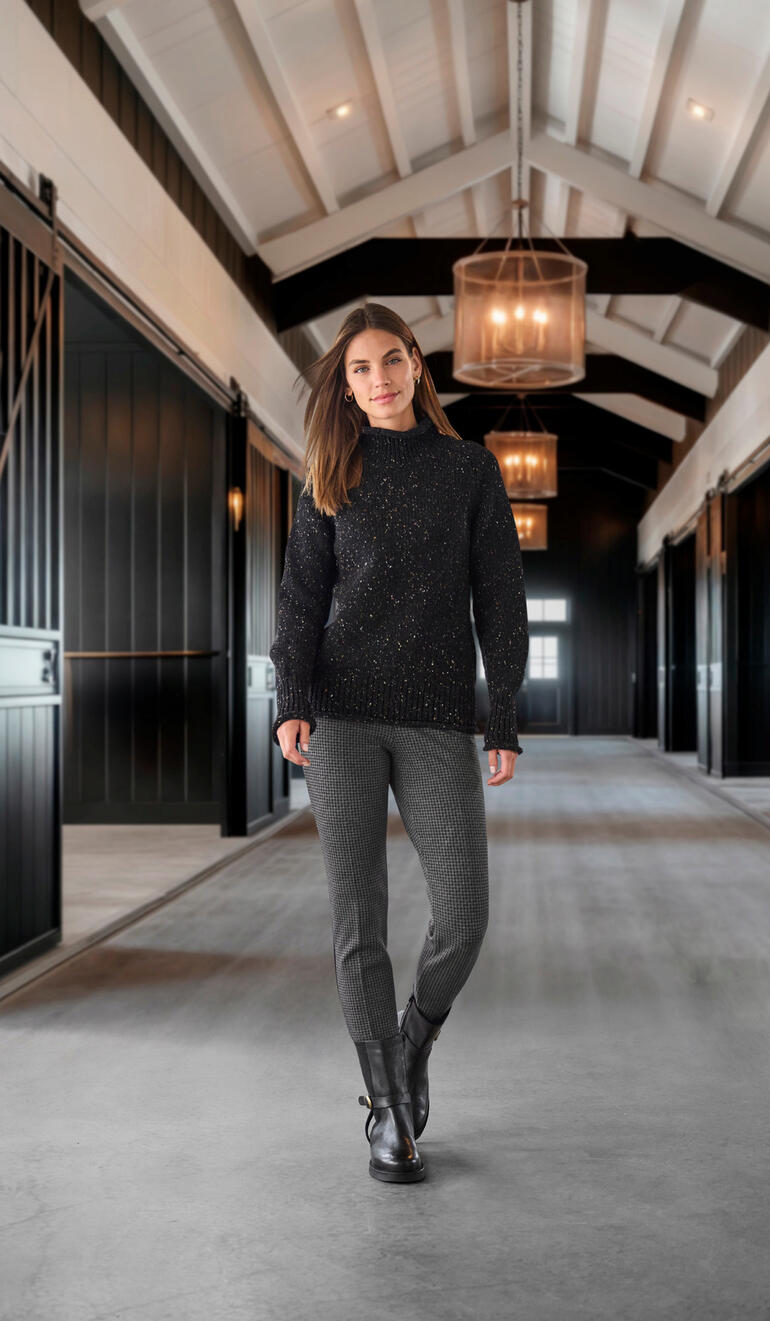 Werner chique bikerboots Vrouw in zwarte trui en houndstooth broek in een moderne hal.