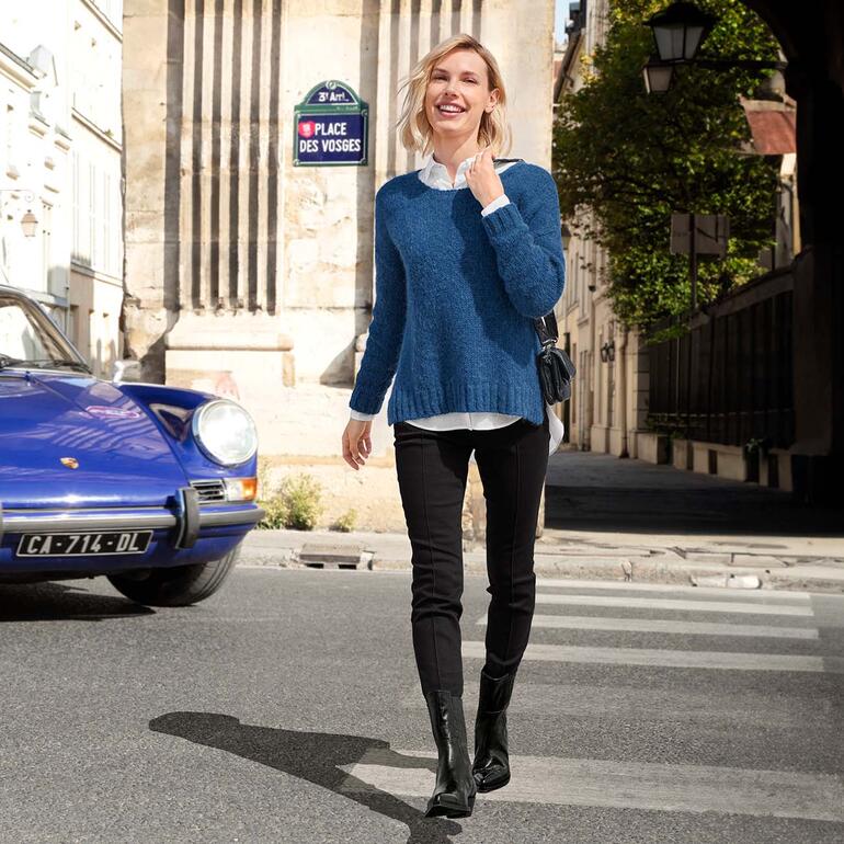 Laura Bellariva westernlaarzen Vrouw in blauwe trui op straat met historische gebouwen.