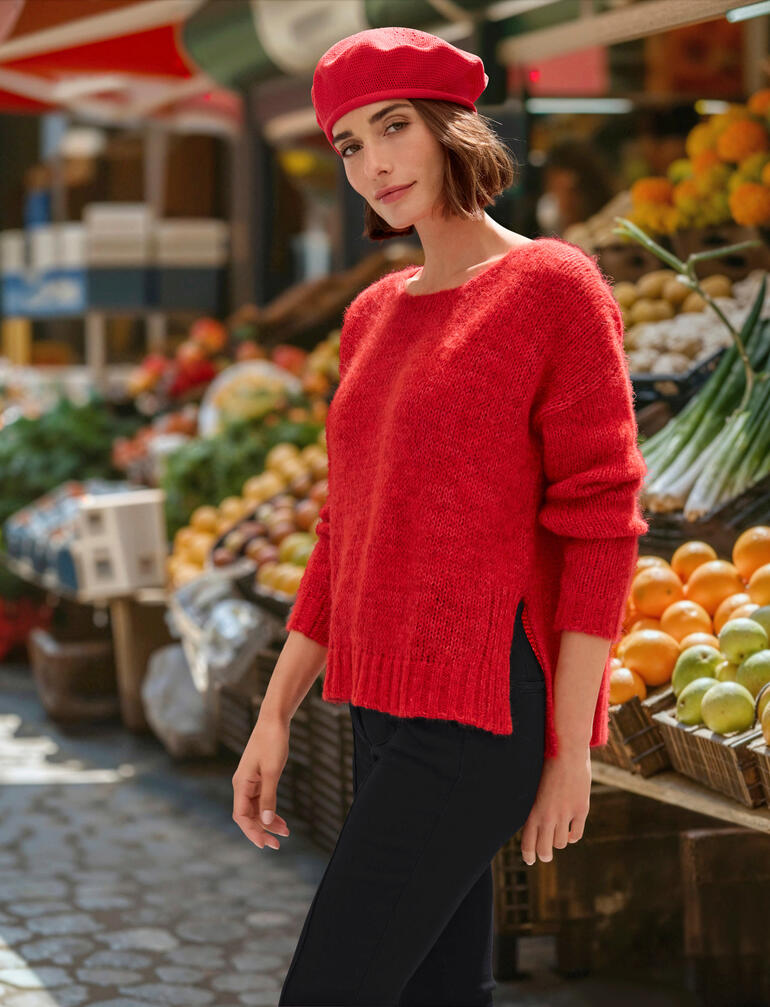 Vrouw in een rode alpaca feel-good trui op een markt
