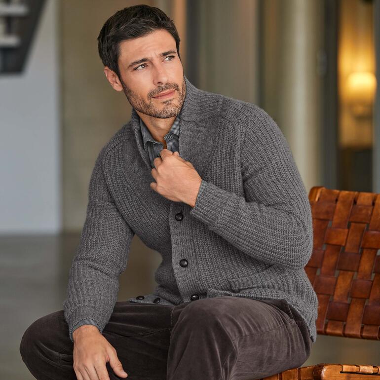 Junghans 1954 12-ply kasjmiercardigan Man in grijze kasjmier cardigan, licht glimlachend.