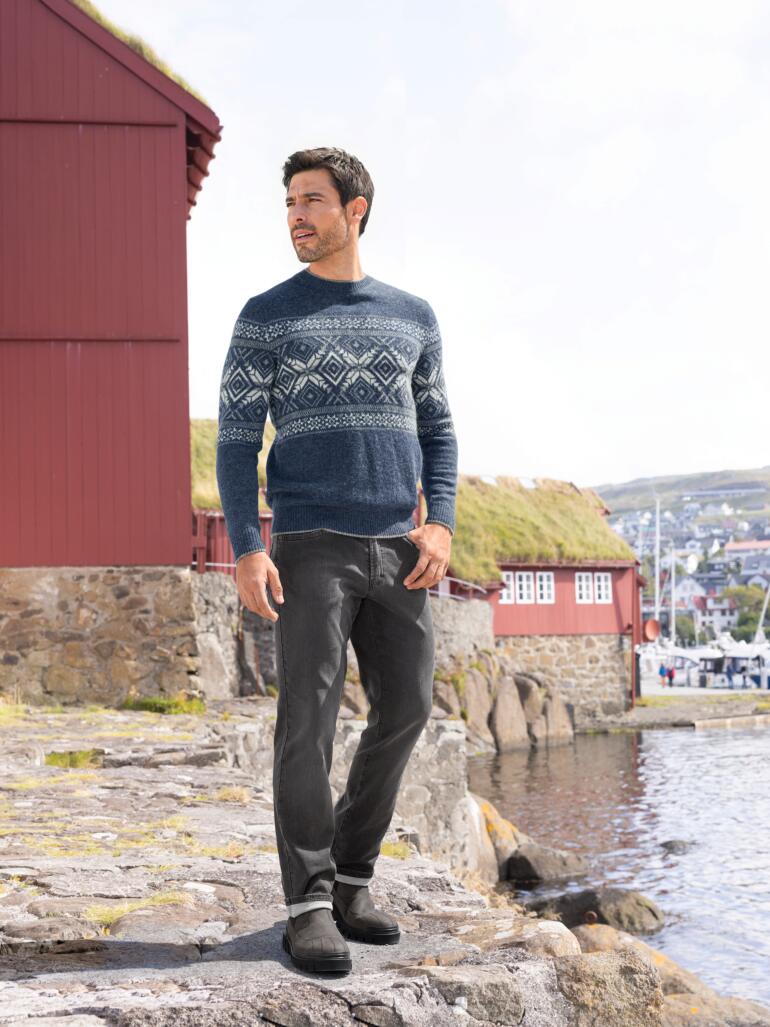 Franz Gustav lichte Chelsea-boots Man in Noorse trui en jeans staat bij het water.