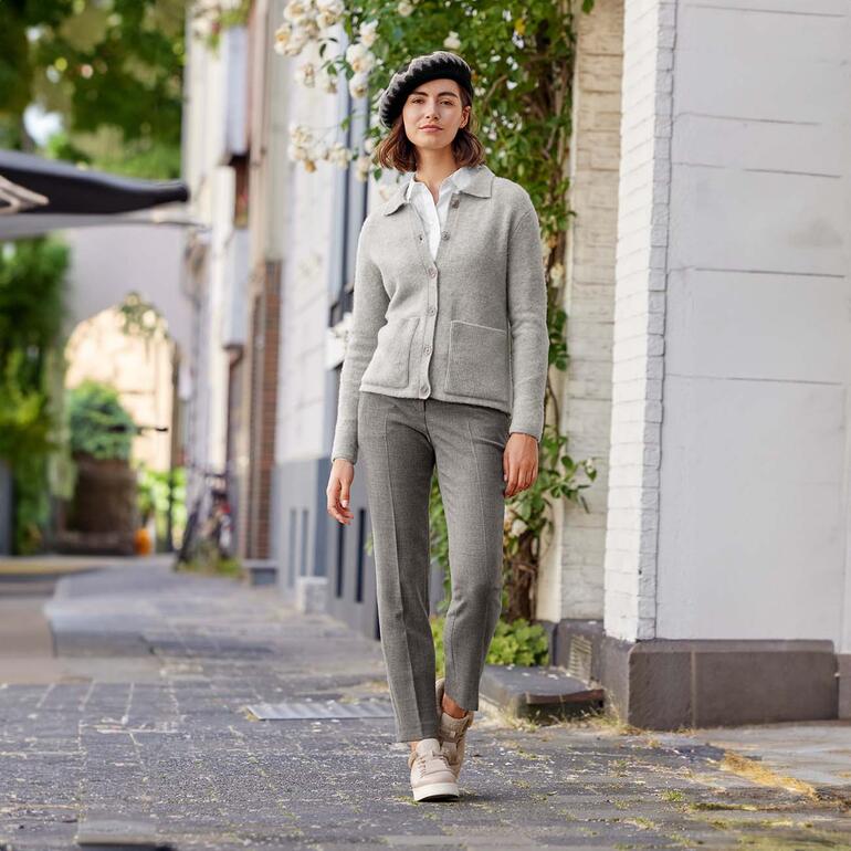 Vrouw in grijze Feel-Good cardigan met baret, staat op straat in de stad.