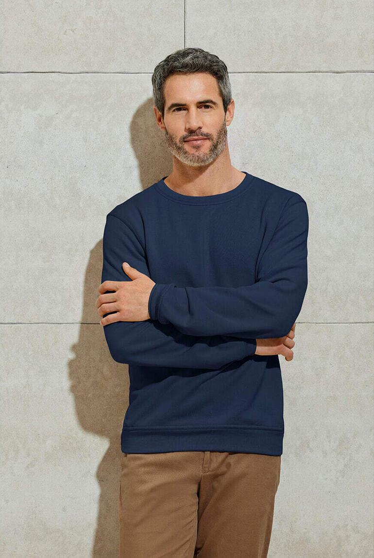 Man in een blauwe kasjmier sweatshirt met gekruiste armen
