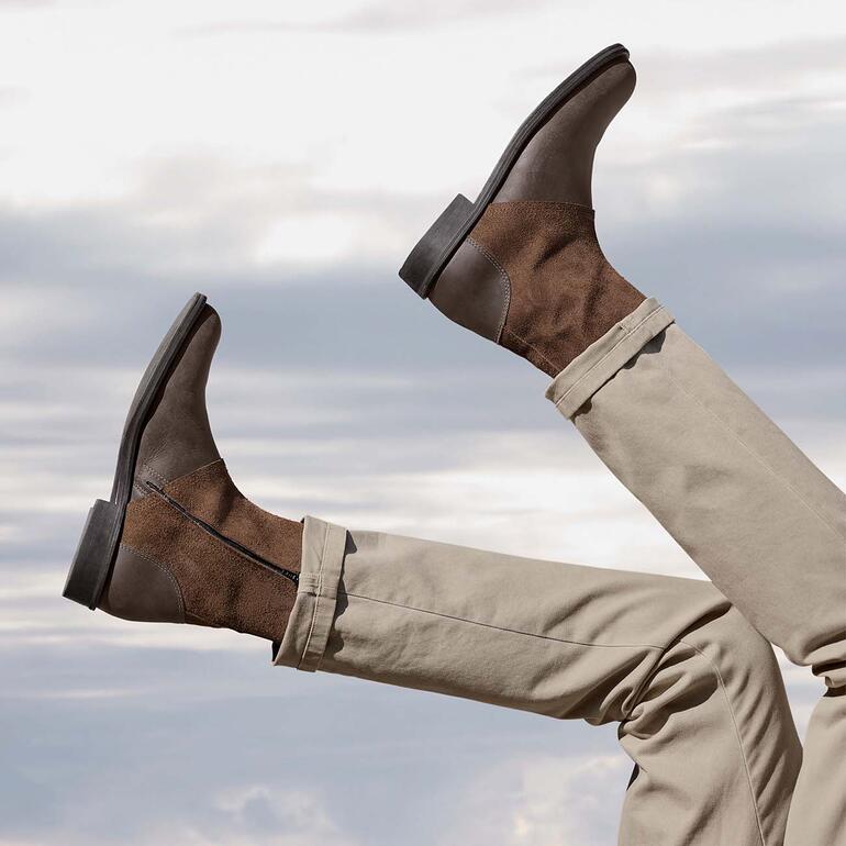Turduli boots van buffelleer Bruine buffellederen laarzen die met de voeten omhoog worden gehouden