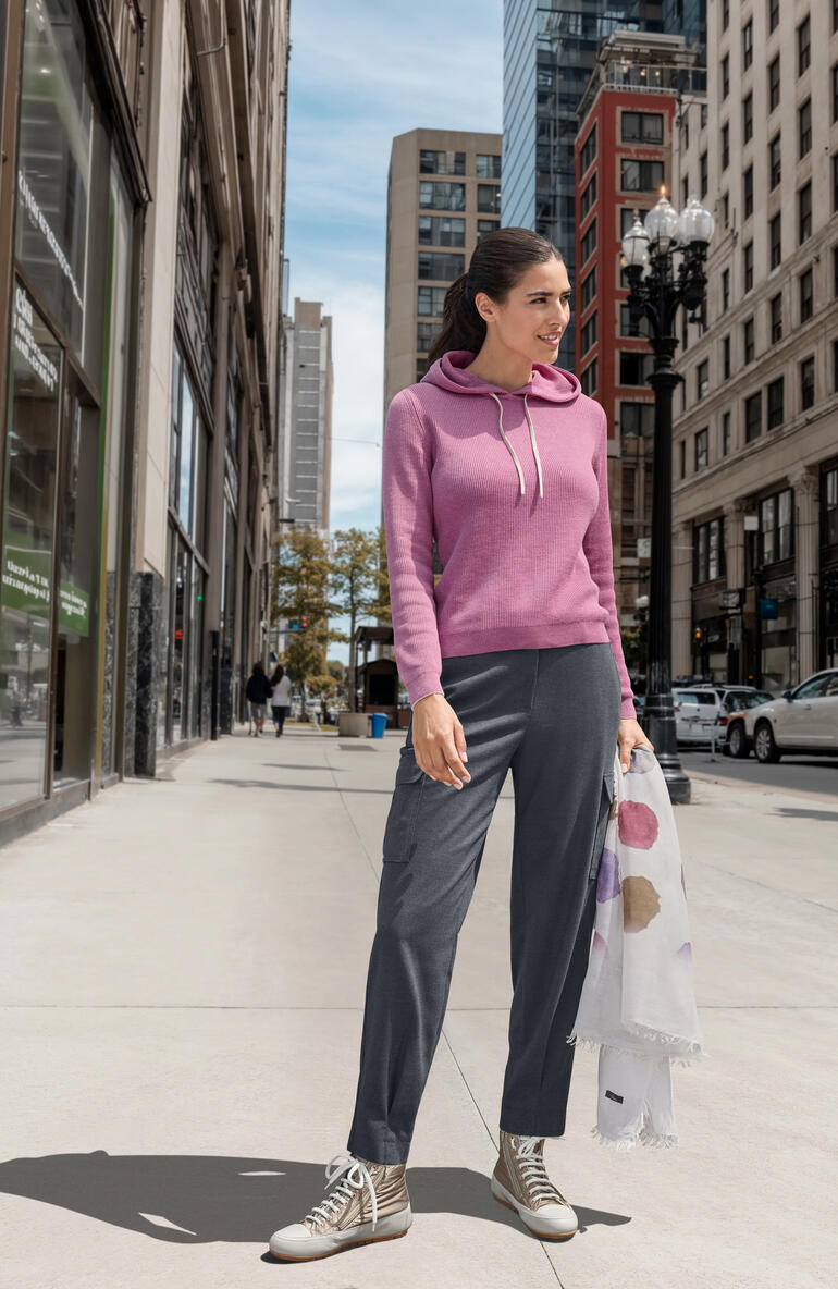 Vrouw in een roze hoodie staat op een stadsstraat.