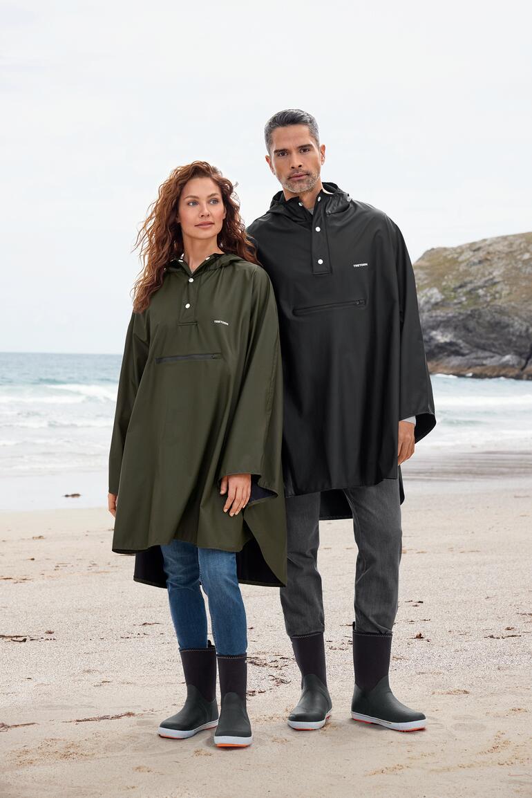 olijf en zwart Unisex-regencape van Tretorn, gedragen door een man en een vrouw op het strand.
