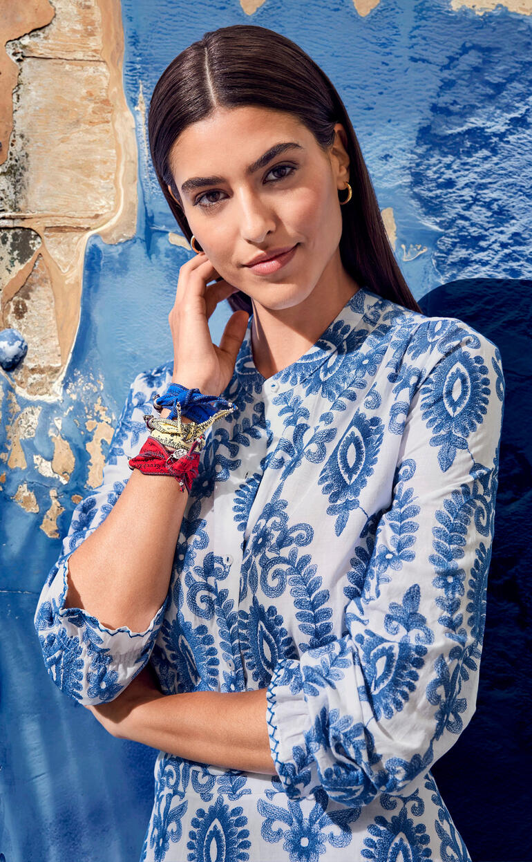 blouse en rok Close-up van een vrouw in een jurk met blauw patroon, die naar de camera lacht.