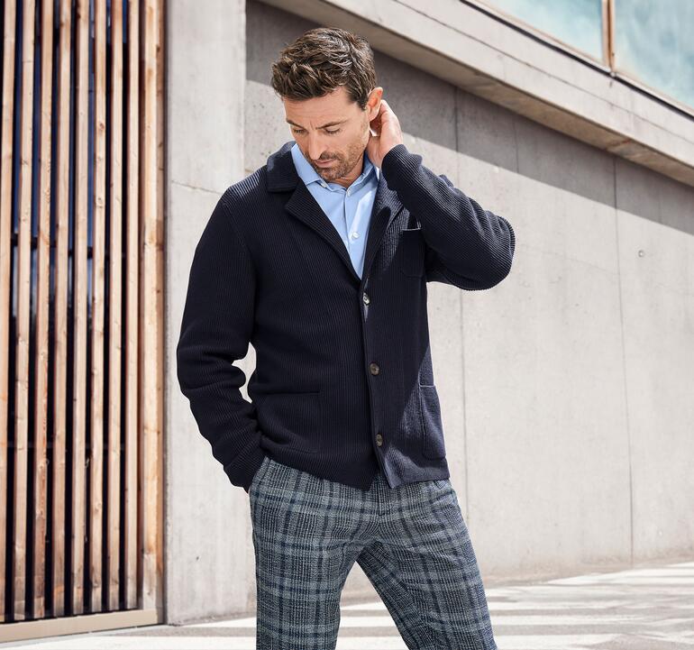 Man in Pima ribbrei-jack kijkt nadenkend naar zijn kleren.