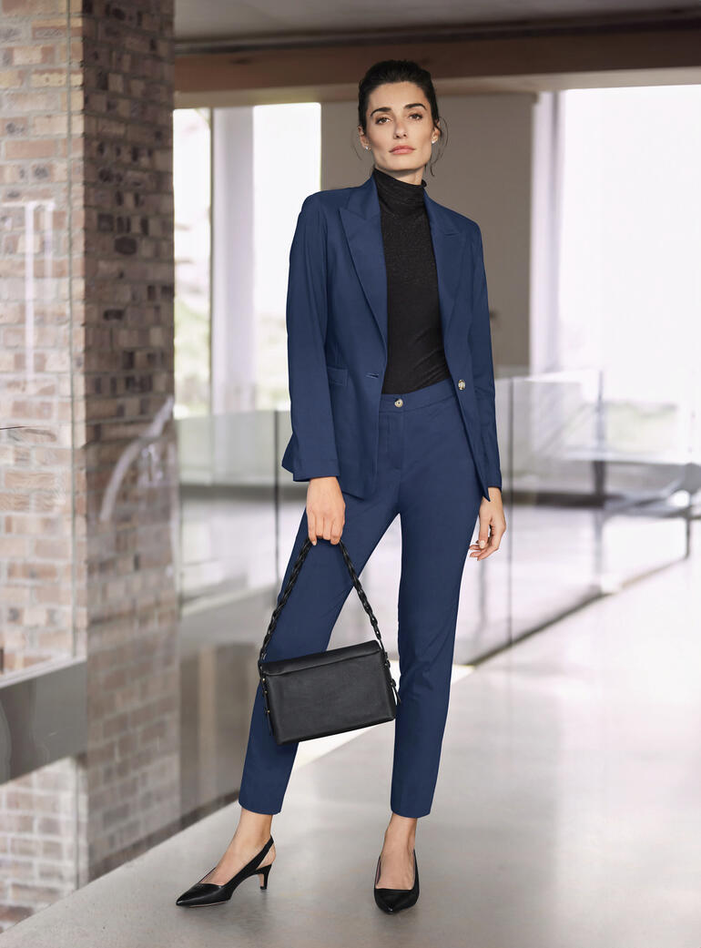 Vrouw in een blauwe stretchpak met een zwarte tas.