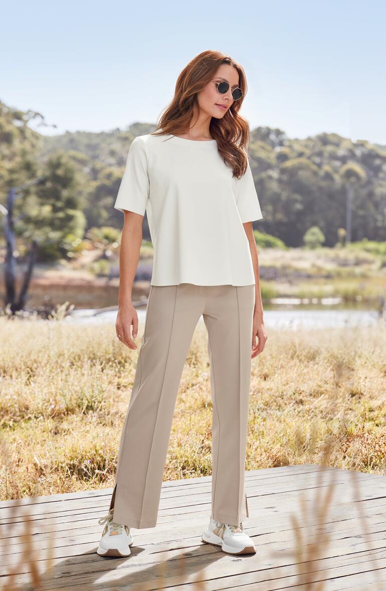 Alexander Smith glamour-sneakers Vrouw in een wit blouse t-shirt en beige broek in een herfsttuin.