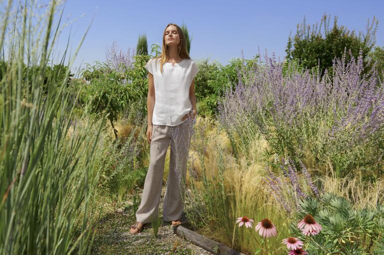 Vrouw in een linnen loungewear ensemble in een tuin.