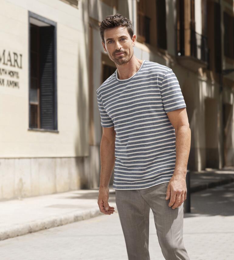 Junghans 1954 gestreept jacquard T-shirt Man in gestreept T-shirt staat op een stadsstraat