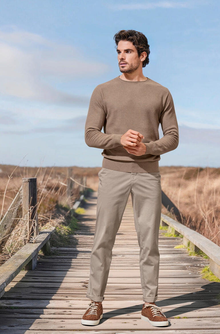 taupe Man in beige trui en lichte broeken op een houten pad