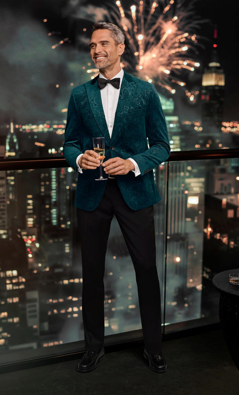 Carl Gross fluwelen colbert met paisleymotief Man in groene paisley fluwelen blazer met uitzicht op de stad.