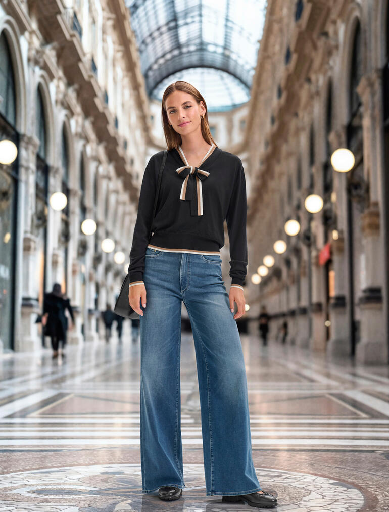 DL1961 comfortabele jersey jeans Vrouw in een elegante outfit met een zwart bindeshirt en wijde jeans in een passage.
