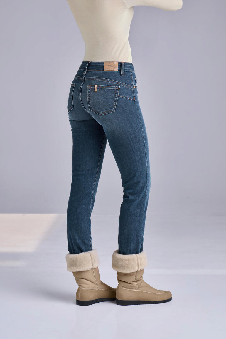 Liu Jo bottom up-jeans ‘Better Denim’ Vrouw toont de achterkant in blauwe jeans en bruine winterlaarzen.