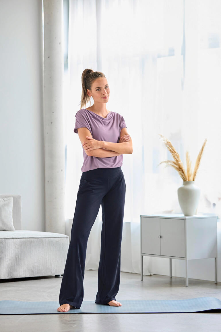 Wijd benige yogabroek in donkerblauwe kleur, gedragen door een vrouw.
