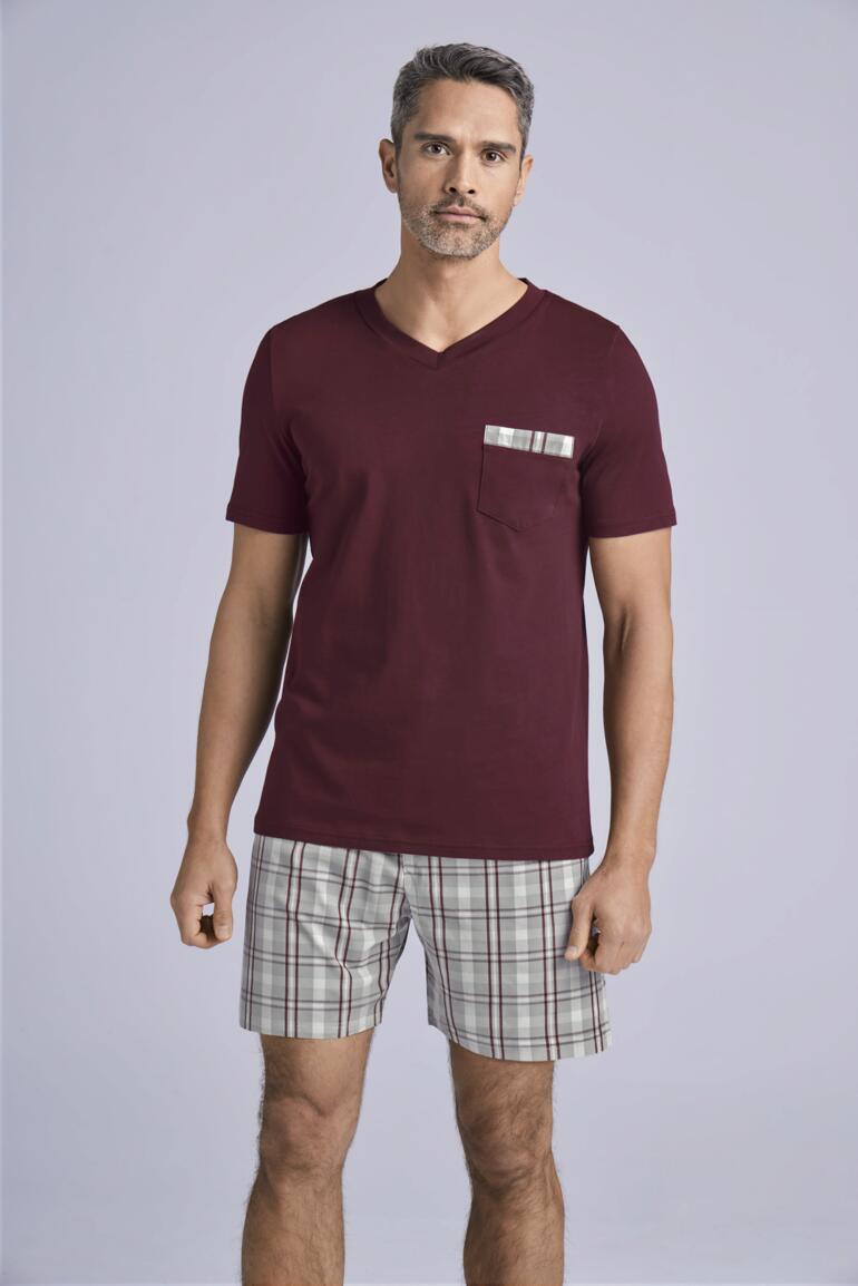 Man in een bordeaux T-shirt met geruit hemd, draagt geruite shorts.