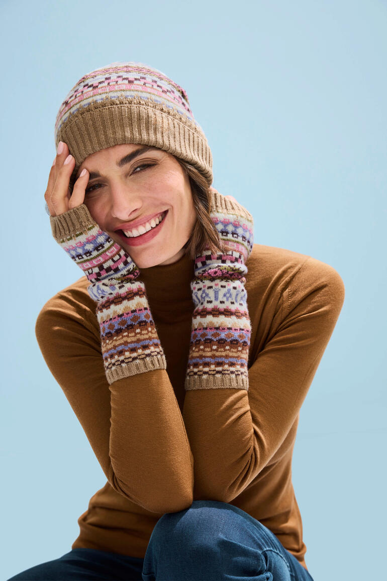 muts en polswarmers Vrouw in jacquard muts en polswarmers, glimlachend in winterse omgeving.