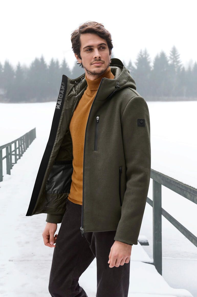 Man in groene wol-fleecejacke met oranje trui aan een bevroren meer.