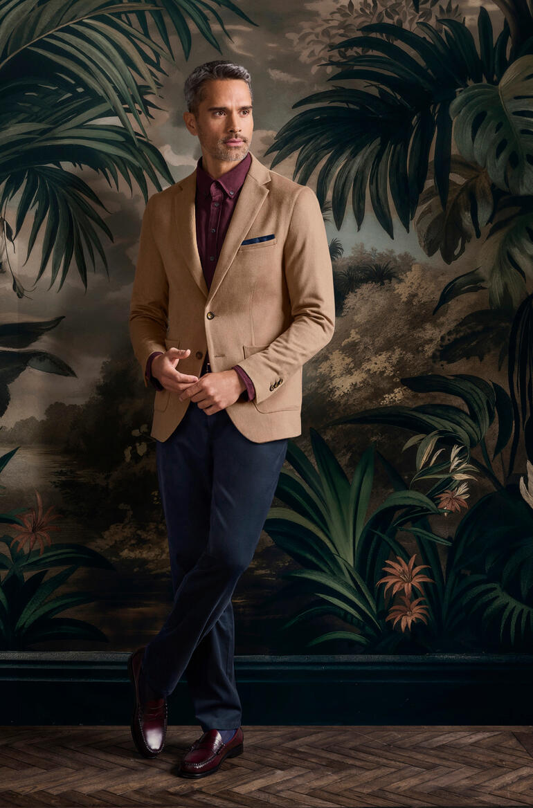 Colbert van kameelhaar Man in kamelenhaar blazer voor een groene achtergrond.