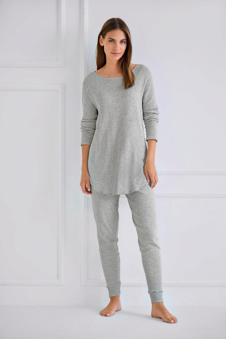 Vrouw in grijs pyjama met bovenstuk en broek