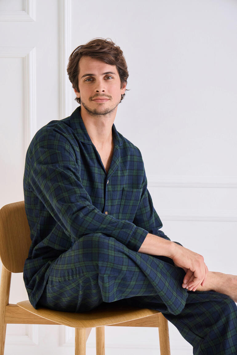Grandfather-flanellen-pyjama Man in een geruit flanellen pyjama, zit op een stoel.