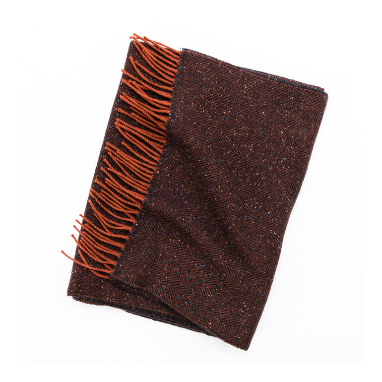 Tweedsjaal Tweed-sjaal in donker oranje en bruin, op een tafel gelegd.