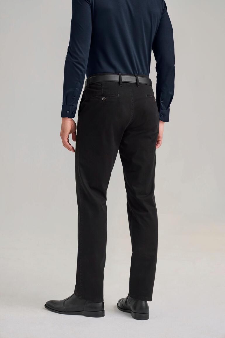 Perma Black-chino Man draagt zwarte Perma-Black-chino's, zichtbaar van achteren.