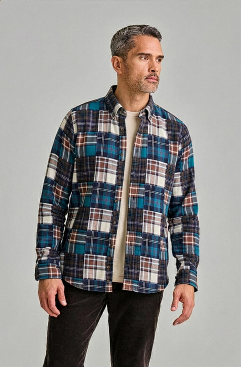 Man staat zijwaarts en draagt een geruite flanellen shirt in blauw met een t-shirt.