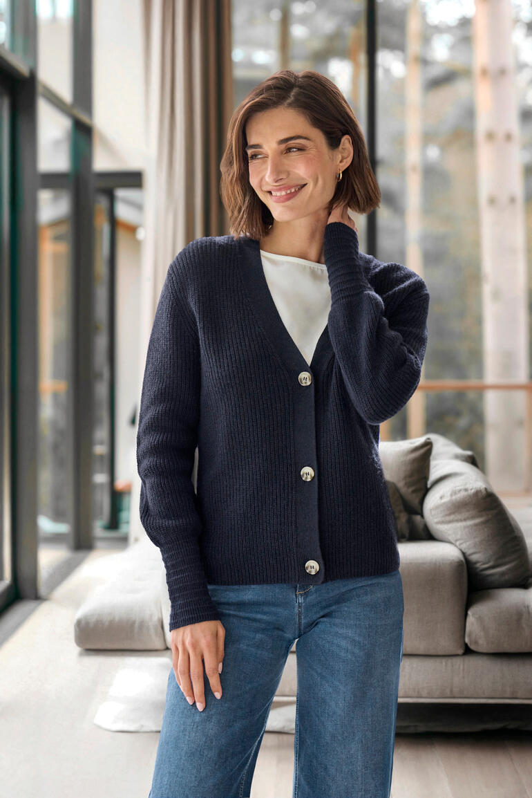 Vrouw draagt een kasjmier-lijn cardigan in donkerblauw met knopen.