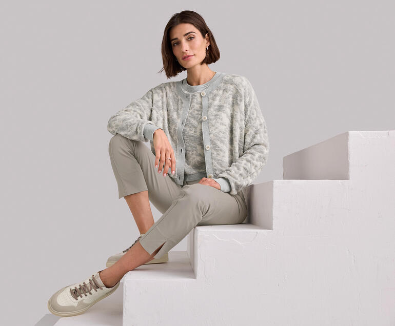 Vrouw zit op een trap, draagt een grijze 3D-Jacquard twinset.