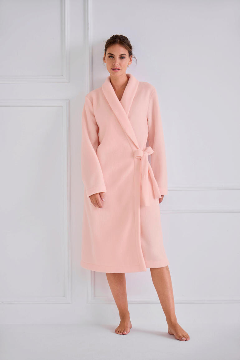 le chat ochtendjas van fleece Vrouw in een roze fleece ochtendjas, staand in volle lengte.